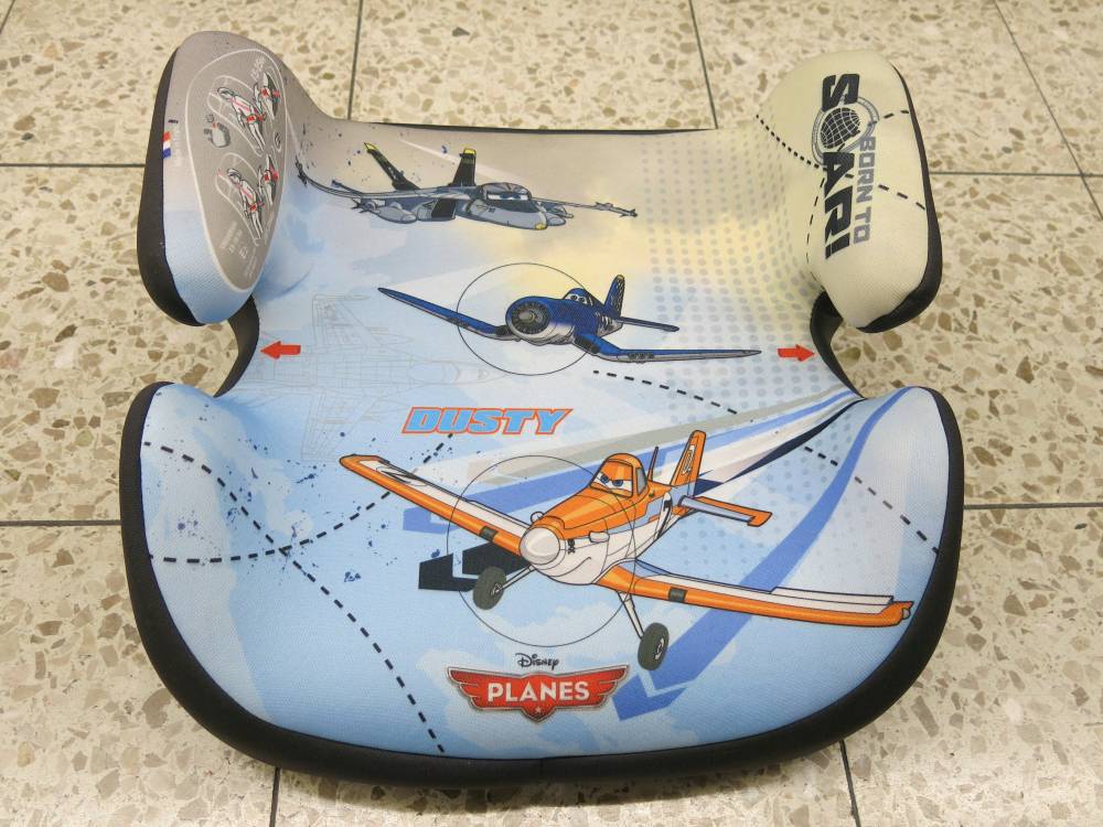 A booster seat for children featuring a Disney Planes design with Dusty and other airplane characters, placed on a tiled floor.